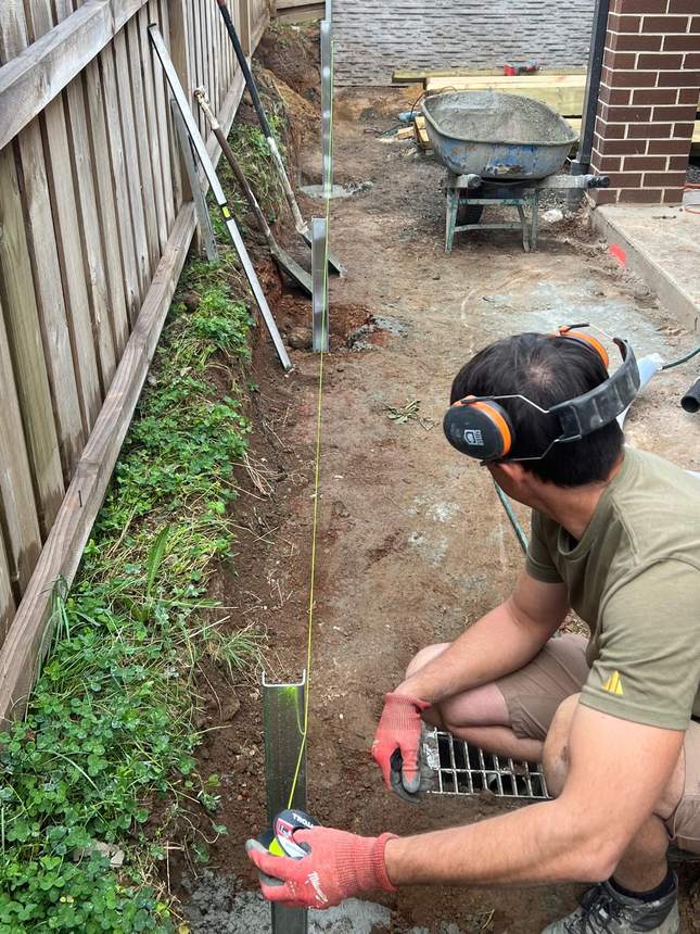 My Home My Garden builder setting out levels with a string line before pouring post footings — Melbourne outdoor construction