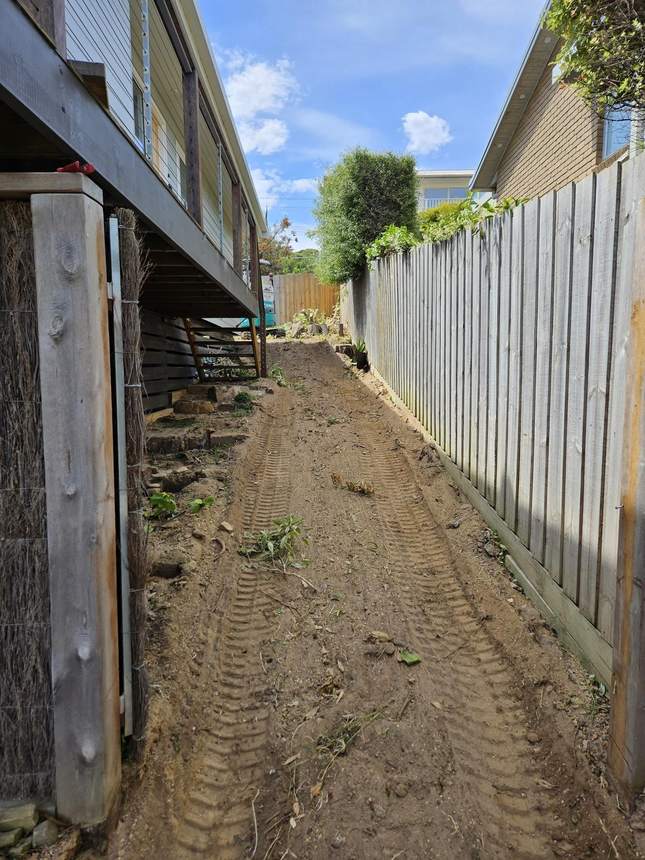 Freshly cut earth face with excavator tyre tracks and existing deck
