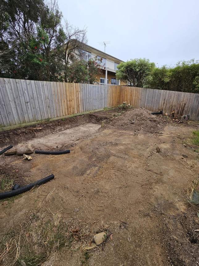 Cleared project area with excavated earth and drainage pipe on ground