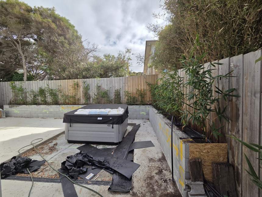 Wide shot of main area with spa on slab, retaining wall and bamboo planted
