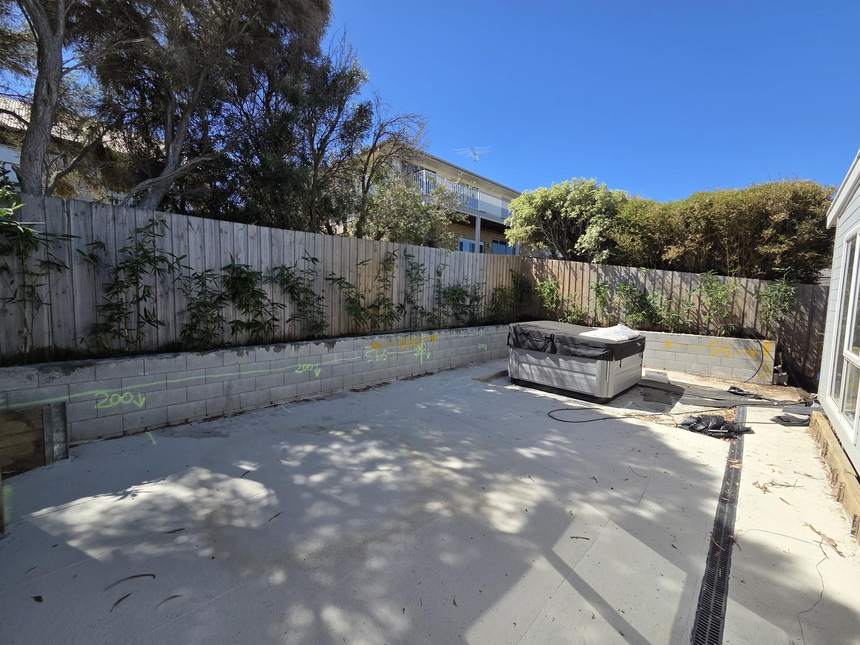 Main spa area with concrete slab, retaining wall, spa and bamboo
