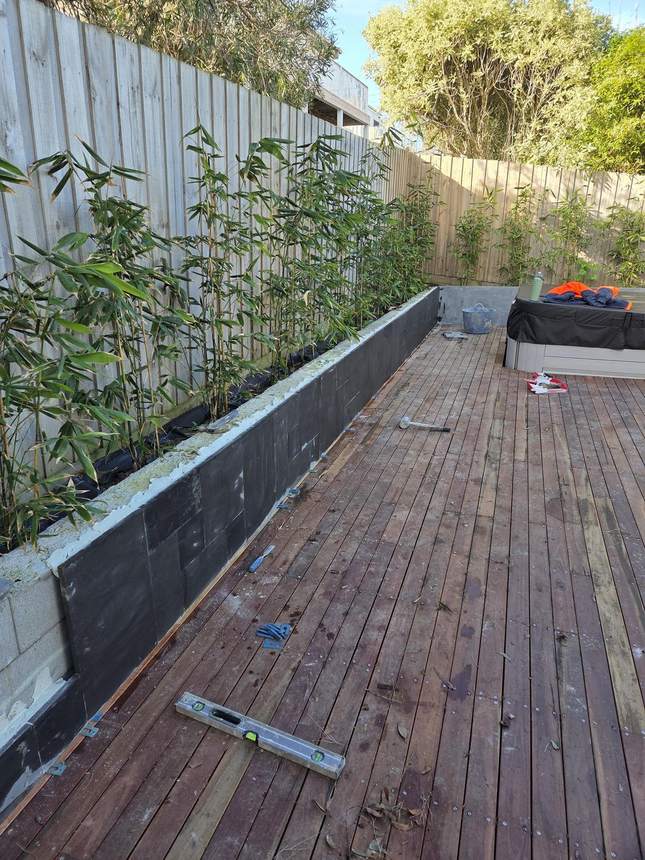 Bluestone tiles being laid on top of the retaining wall with spirit level