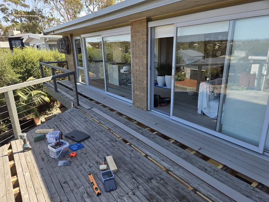 Old deck surface with tools and materials staged, cable wire balustrade visible — work day commences, Jan Juc