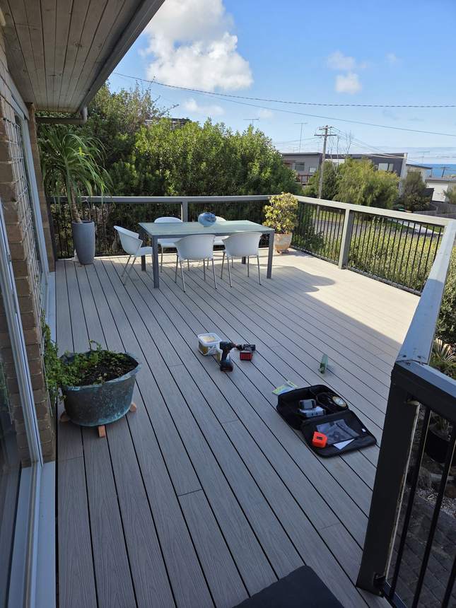 Composite deck with new aluminium balustrade and outdoor lounge furniture being placed, Surf Coast views beyond — Jan Juc