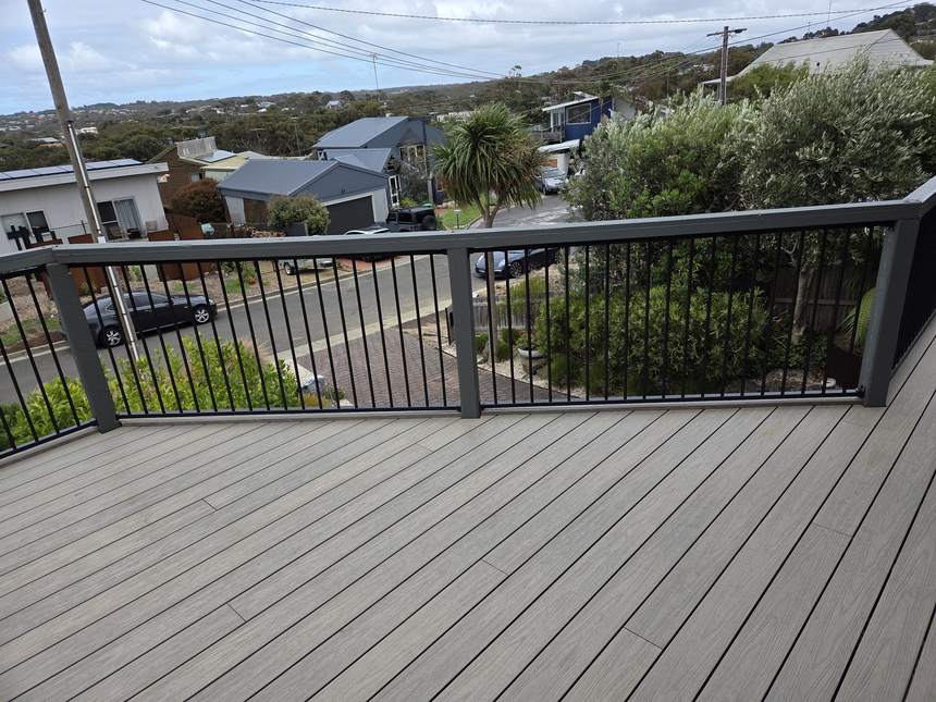 Completed Ash Grey composite deck with dark aluminium frame balustrade wrapping the perimeter — Jan Juc views beyond