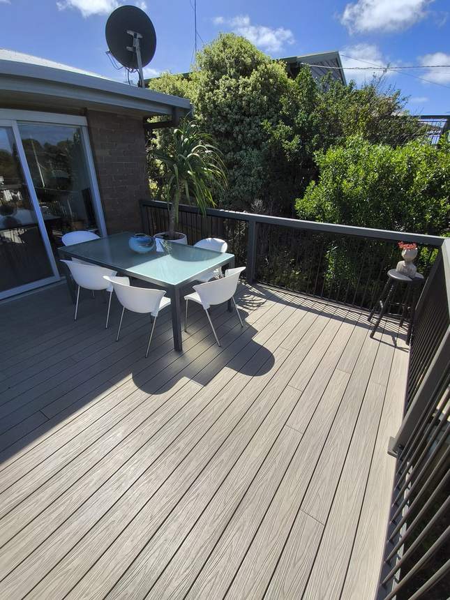 Outdoor dining setting on composite deck — glass table, white chairs and garden agaves, Jan Juc