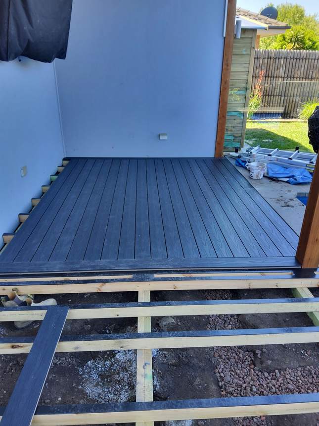 Dark charcoal composite deck boards being laid alongside the pool — Pakenham