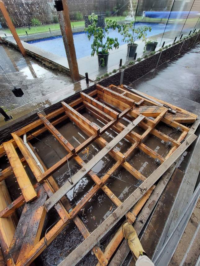 Old deck subframe stripped — timber joists sitting in pooled water, showing structural deterioration — Pakenham
