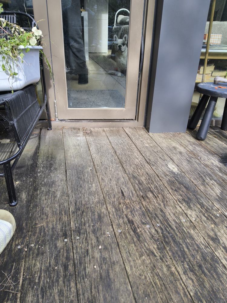 Weathered timber deck boards at the doorway before replacement