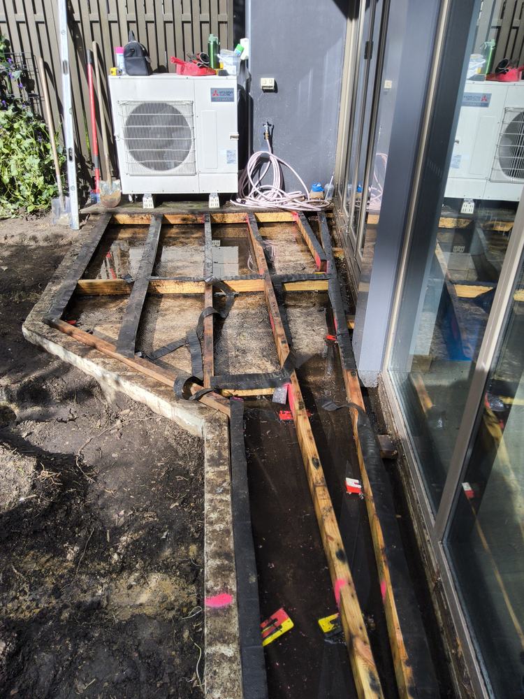 Old deck frame exposed, wedged between concrete on packers with no fixings