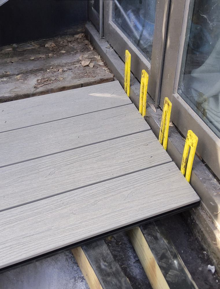 First composite boards at the door with yellow 5mm spacers against the house