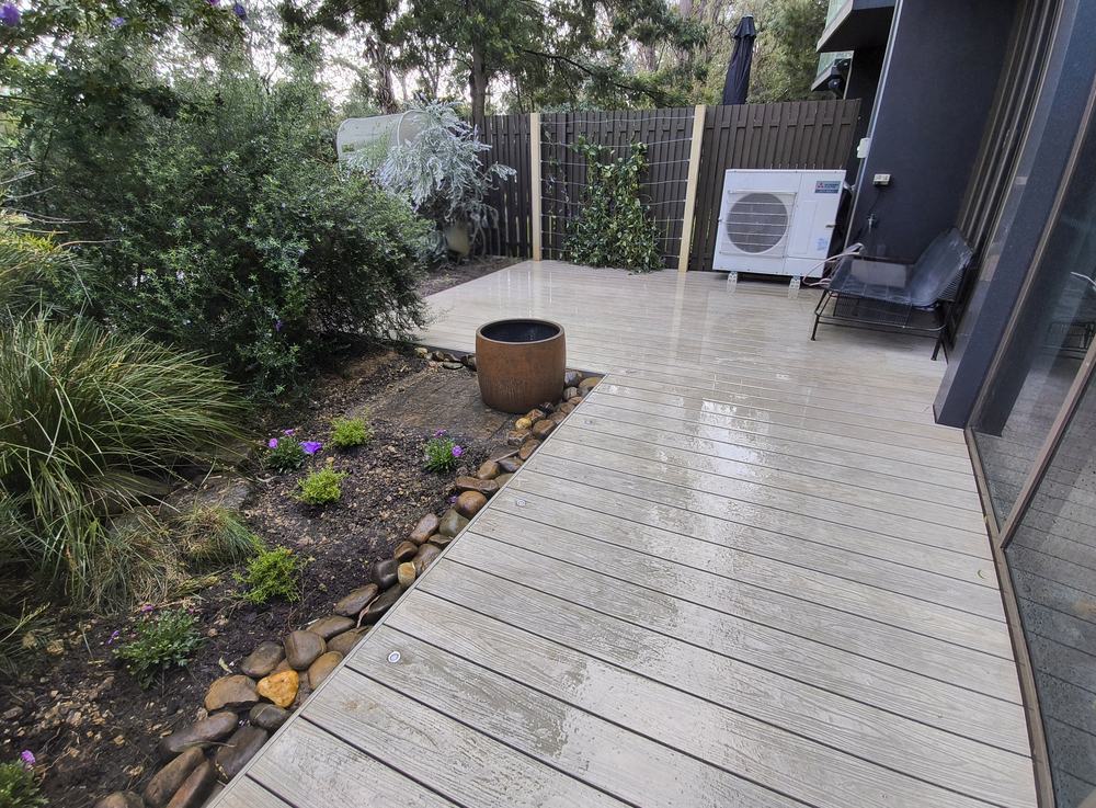 Completed composite deck along the side of the house with garden bed