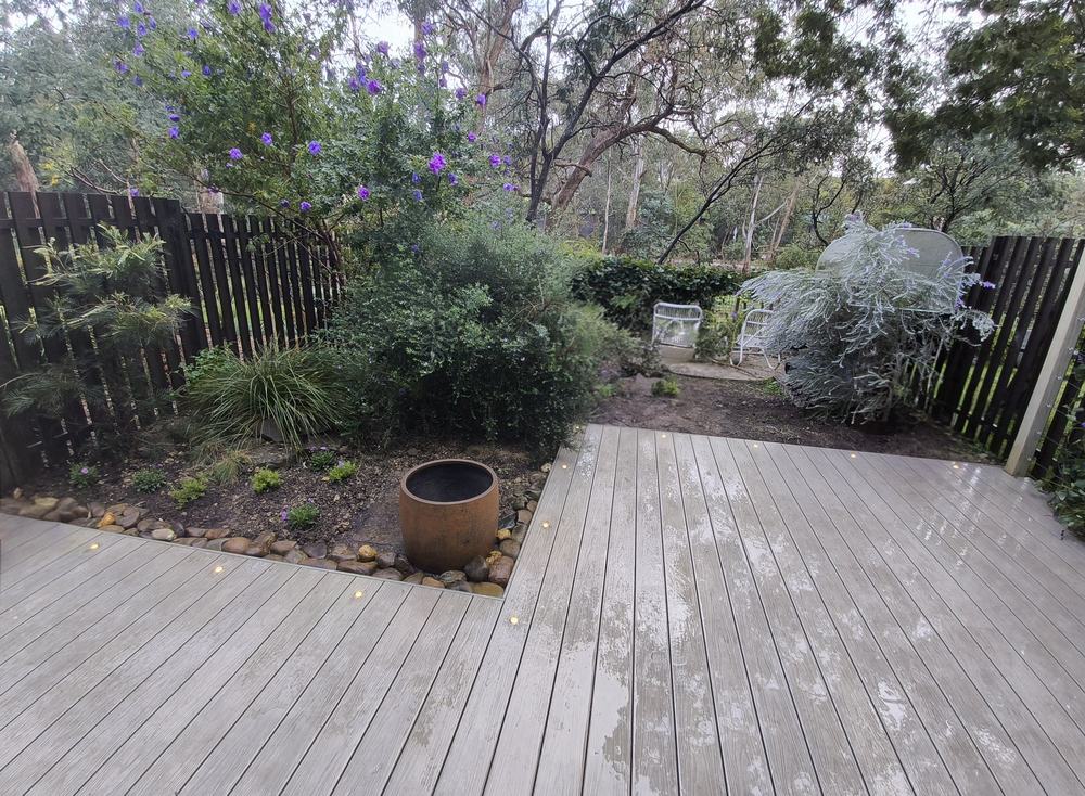 Finished composite deck extension surrounded by garden