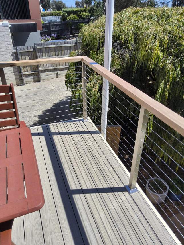 Deck and balustrade from the side — wire taut from post to post, the rebuilt frame visible beneath, Seaford