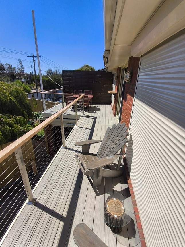 The finished composite deck — marine-grade wire balustrade and Tasmanian oak handrail on the rebuilt balcony, Seaford