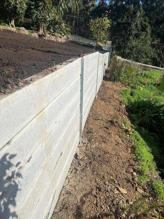 Finished retaining wall with the bank backfilled and the yard reclaimed level — Templestowe